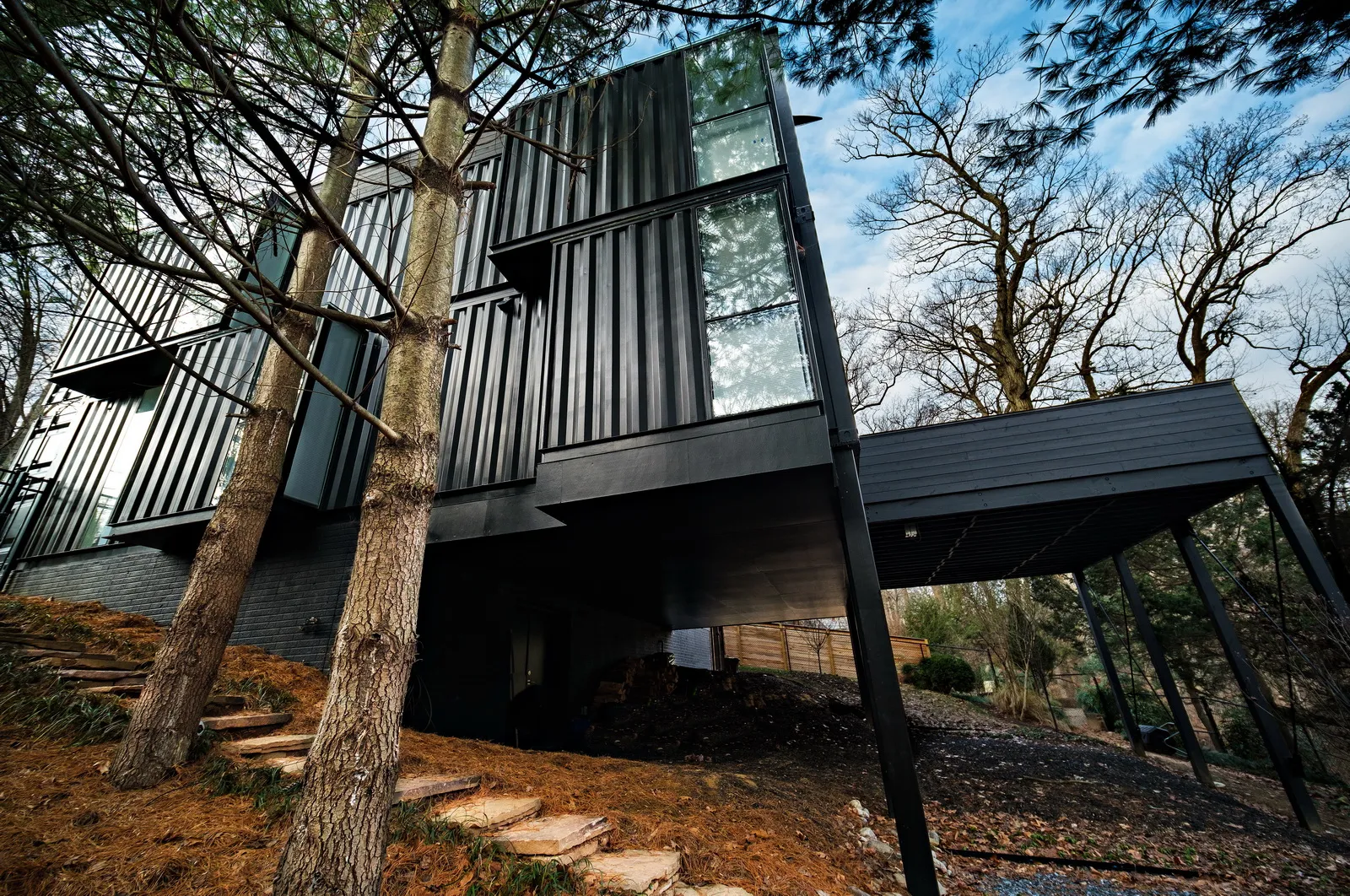 An exterior shot of a unique container house, featuring large windows and a minimalist architectural style.