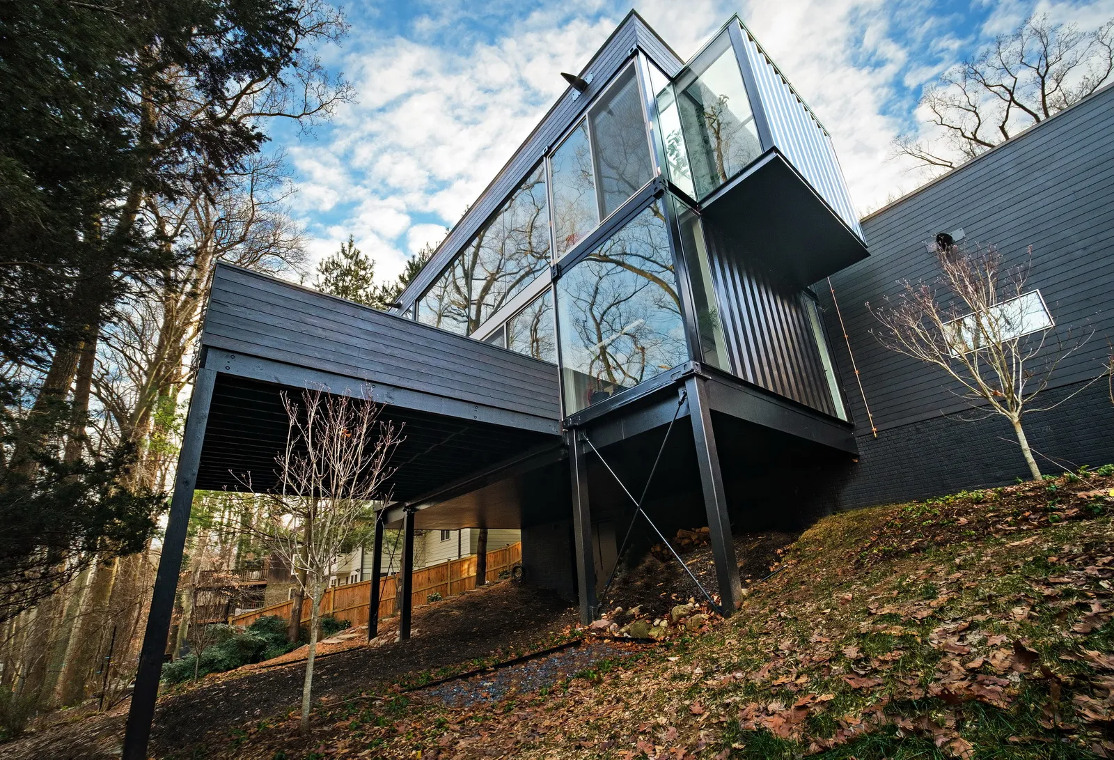 A stylish, multi-story container house with a vibrant exterior and a surrounding landscaped yard.